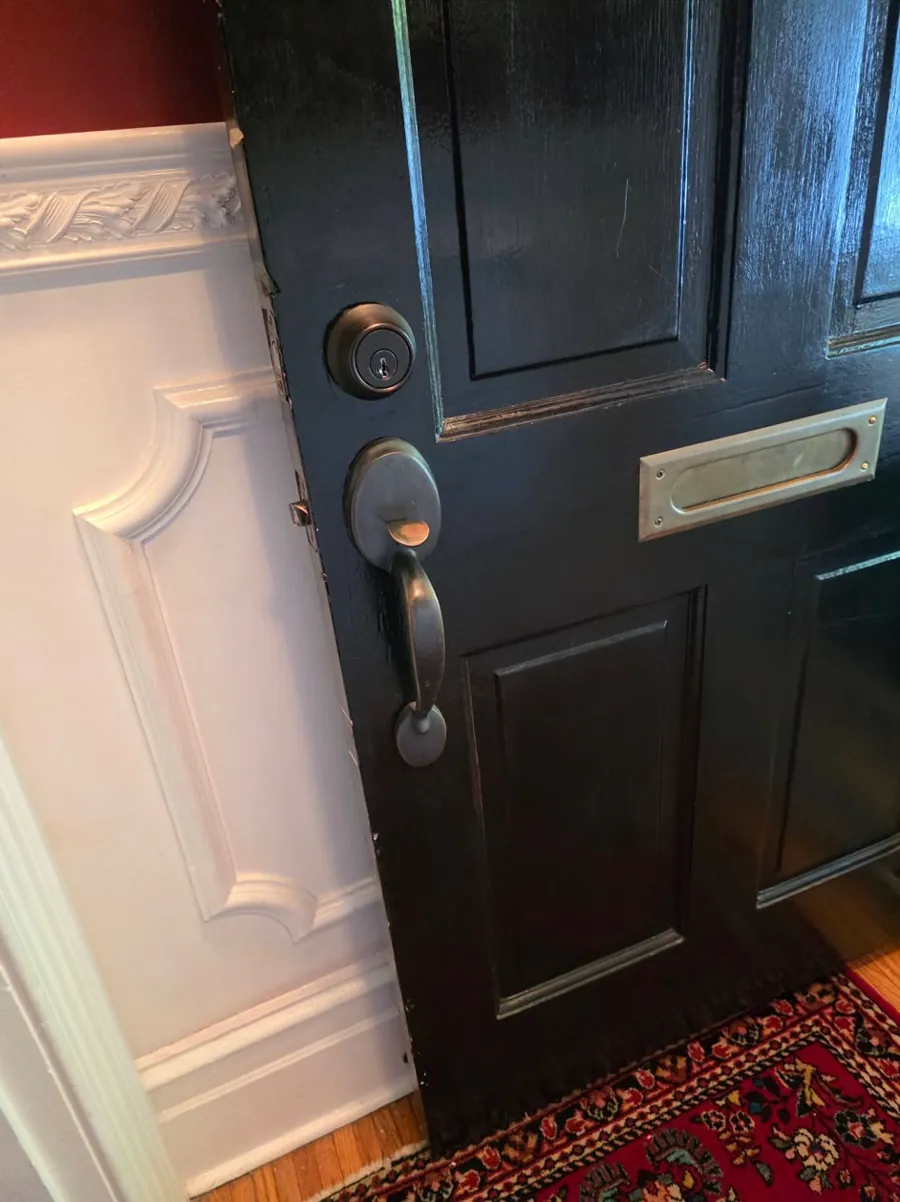 Black paneled front door with a deadbolt, a lever handle and a mail slot