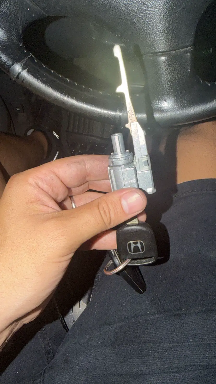 Hand holding a car key and the lock cylinder taken out of the car door