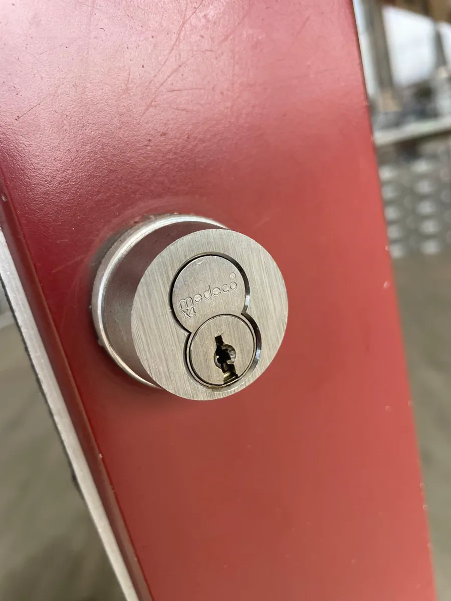 Round high-security lock cylinder in a red steel door