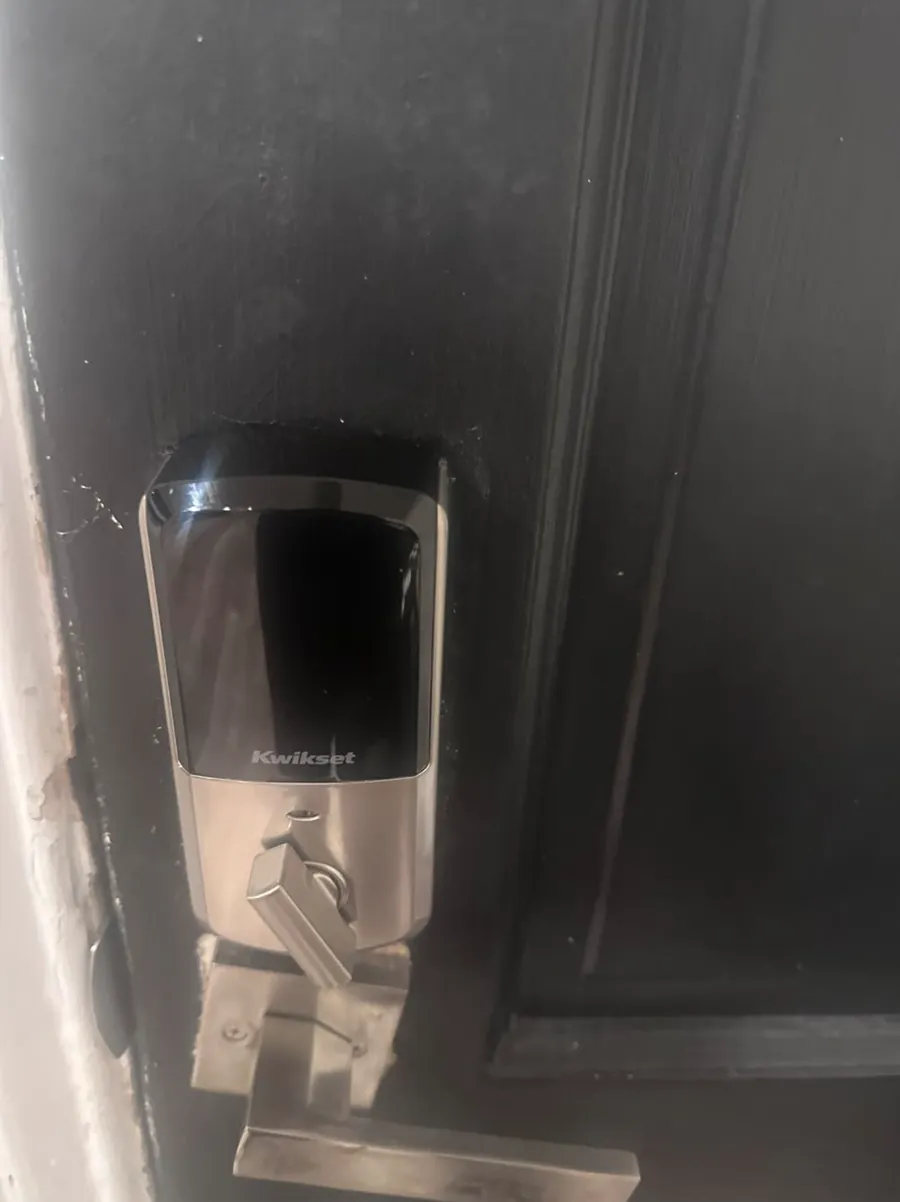 Smart deadbolt with a keypad above a lever handle on a dark front door