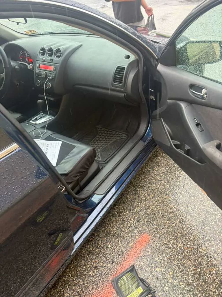 Open passenger door of a black sedan parked in the street